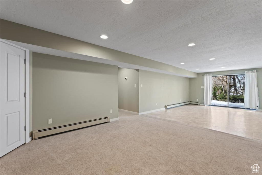 Basement featuring a baseboard radiator, recessed lighting, baseboard heating, carpet flooring, and a textured ceiling