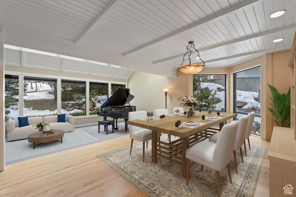 Dining space with vaulted ceiling with beams, wood ceiling, and light wood-style floors