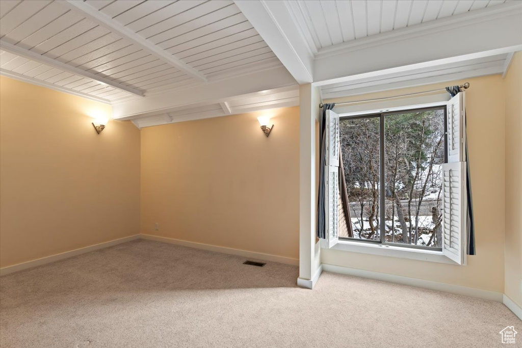 Unfurnished room featuring baseboards, carpet, visible vents, and beam ceiling