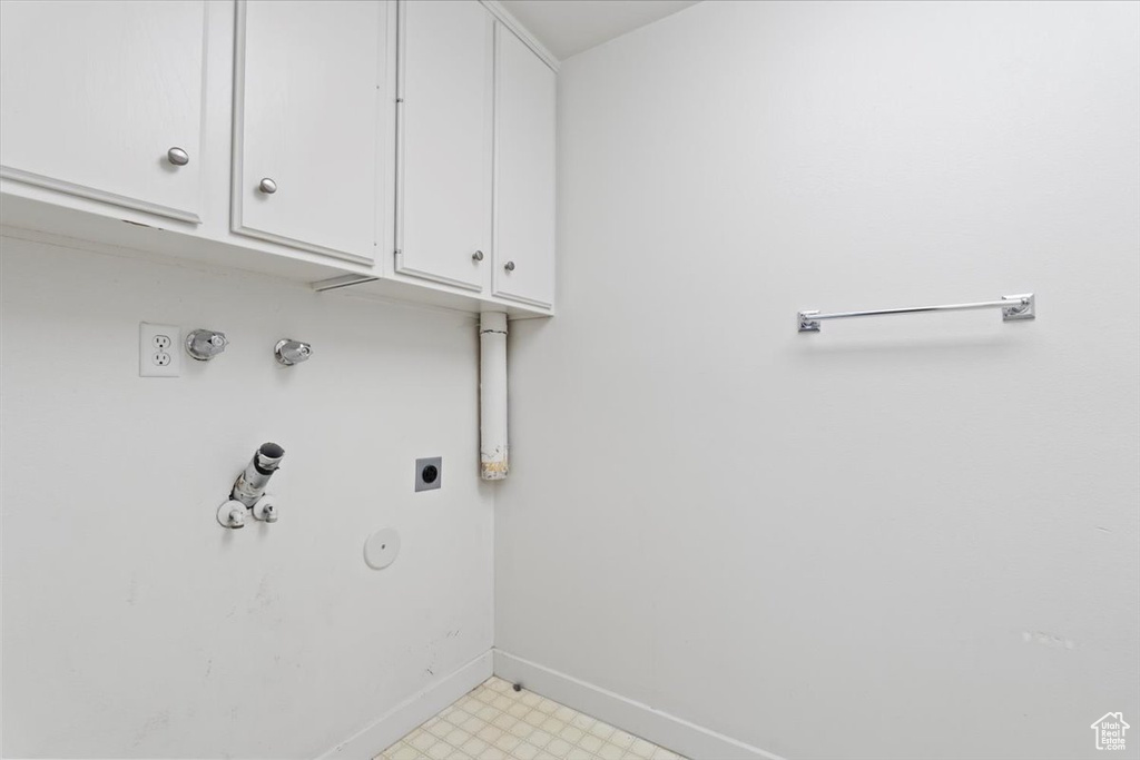 Washroom featuring gas dryer hookup, baseboards, cabinet space, light floors, and electric dryer hookup