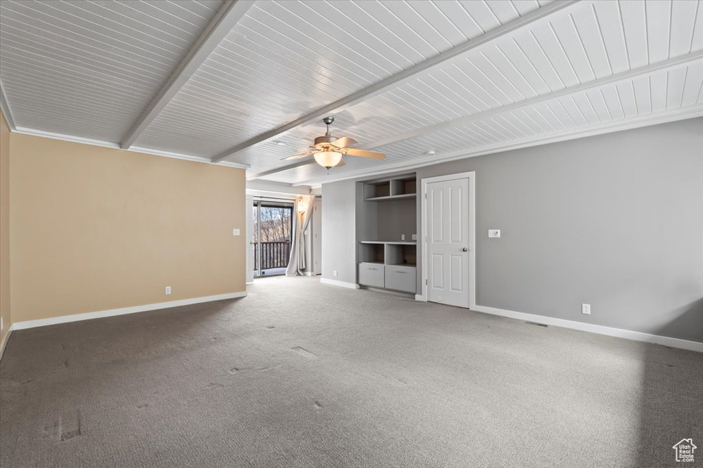 Unfurnished living room featuring carpet floors, beam ceiling, baseboards, and a ceiling fan