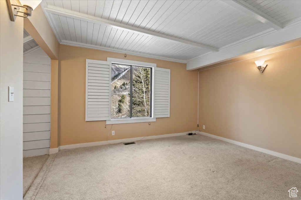 Carpeted spare room with beamed ceiling, visible vents, and baseboards