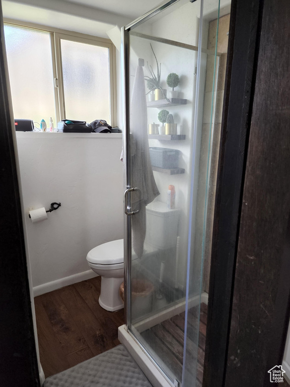 Bathroom with a shower with shower door, toilet, and hardwood / wood-style flooring