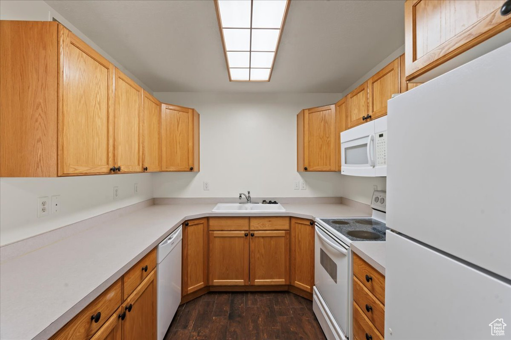 Kitchen with white appliances, light brown cabinets, dark hardwood / wood-style floors, and sink