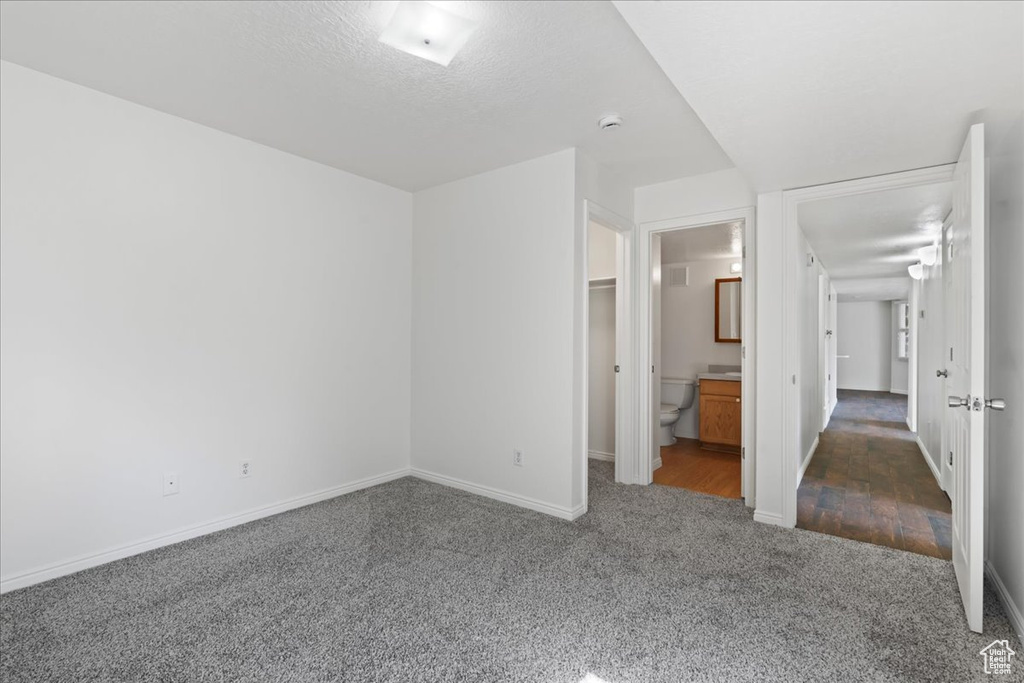 Unfurnished bedroom featuring dark wood-type flooring, a textured ceiling, and connected bathroom