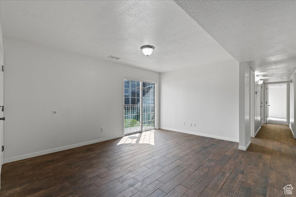 Unfurnished room with dark wood-type flooring and a textured ceiling