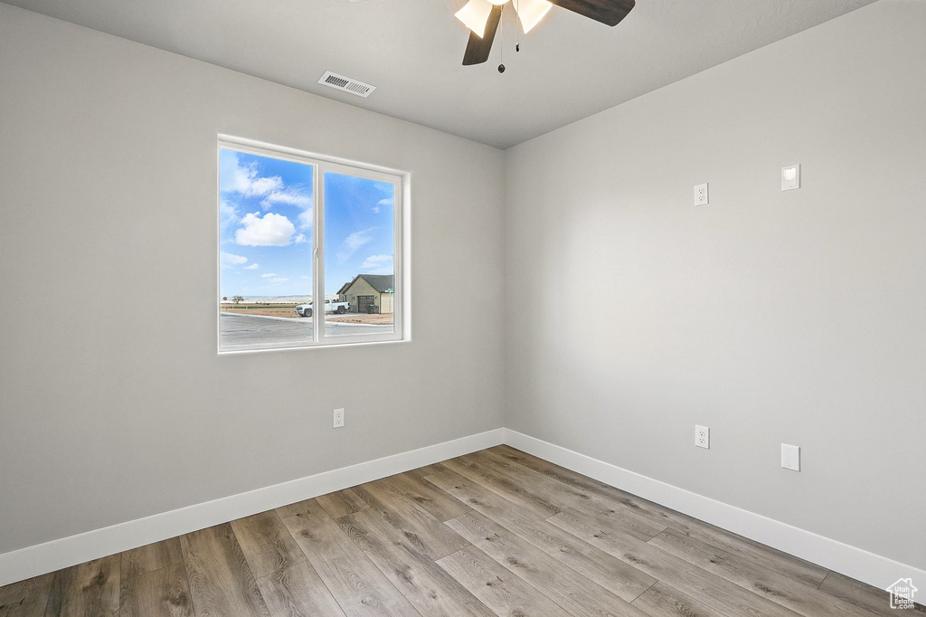 Unfurnished room featuring light wood-style flooring, ceiling fan, baseboards, and visible vents