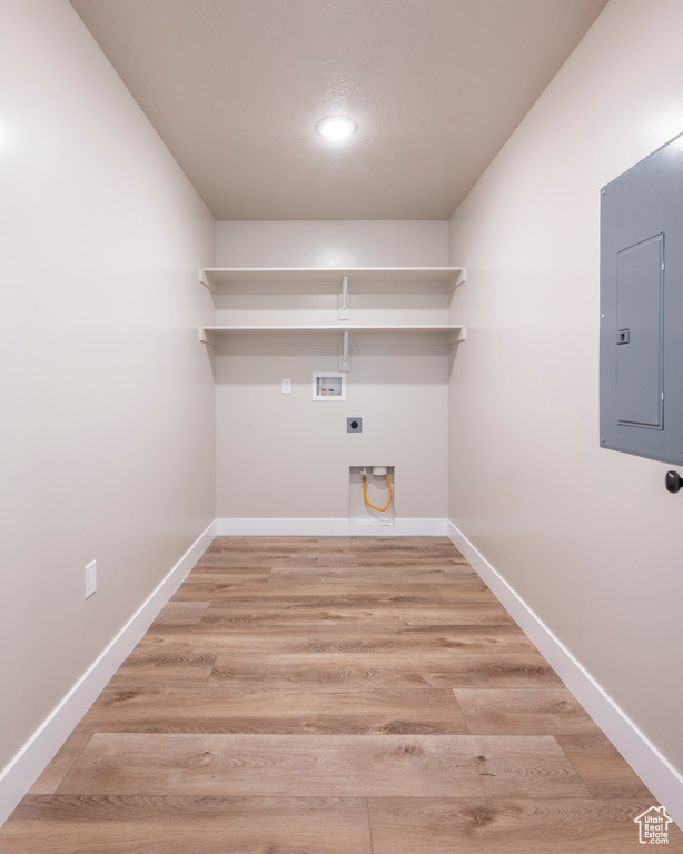 Laundry room with washer hookup, electric panel, light hardwood / wood-style floors, and electric dryer hookup