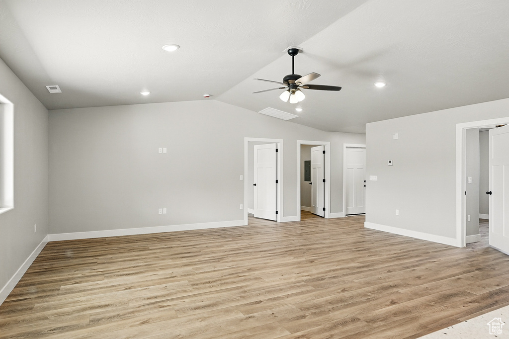 Unfurnished living room featuring light wood-type flooring, ceiling fan, vaulted ceiling, and visible vents