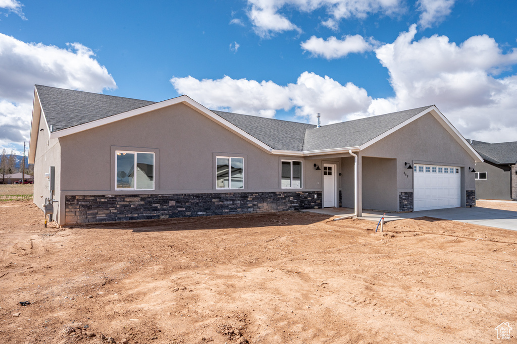 Ranch-style house with roof with shingles, stucco siding, driveway, stone siding, and a garage