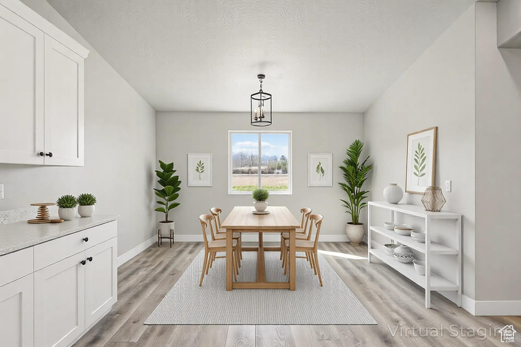 Dining space with baseboards, light wood-type flooring, and a textured ceiling
