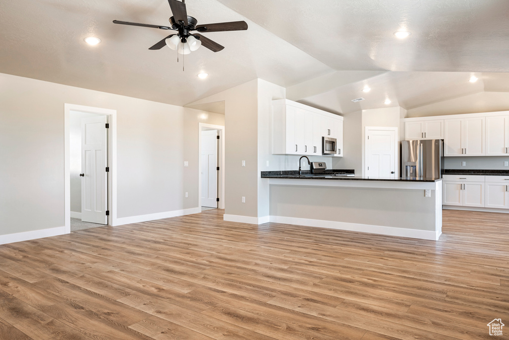 Kitchen featuring vaulted ceiling, stainless steel appliances, light hardwood / wood-style floors, kitchen peninsula, and ceiling fan