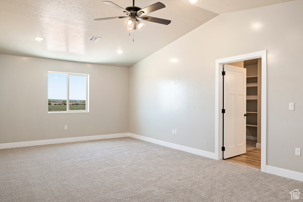 Carpeted empty room featuring lofted ceiling and ceiling fan