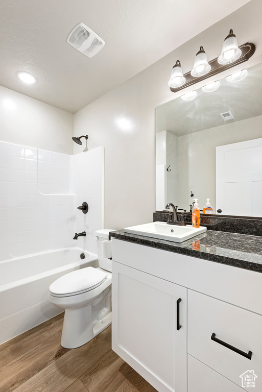 Full bathroom with hardwood / wood-style floors, toilet, tub / shower combination, and vanity