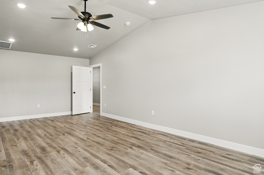 Unfurnished room featuring ceiling fan, light wood-type flooring, visible vents, vaulted ceiling, and baseboards
