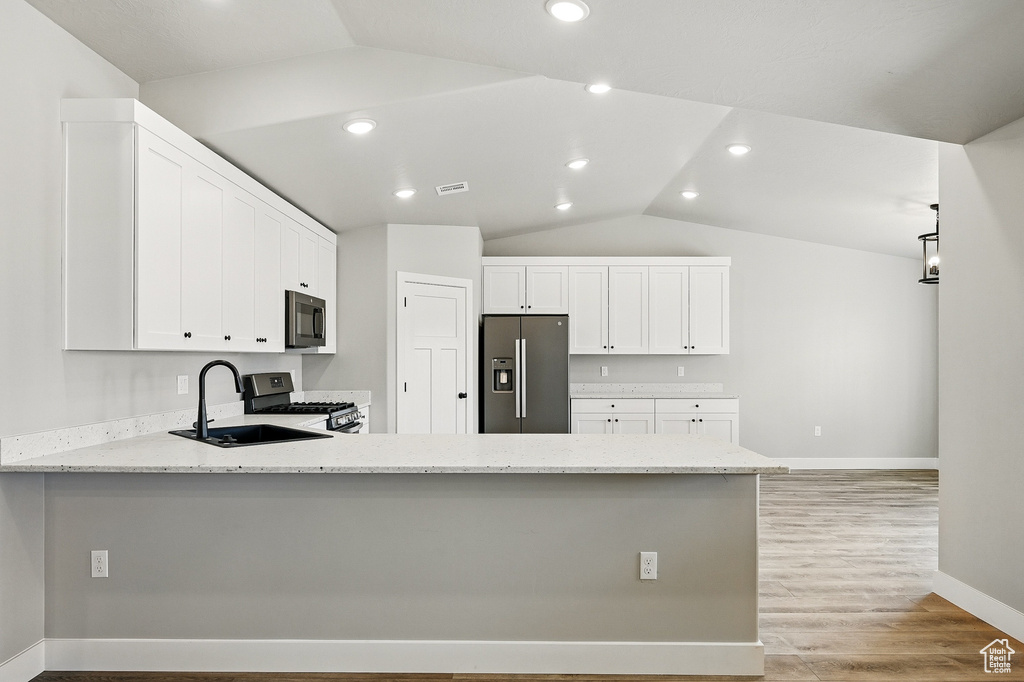 Kitchen with a sink, appliances with stainless steel finishes, a peninsula, and lofted ceiling