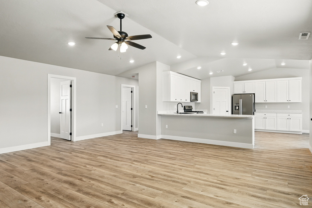 Kitchen with white cabinetry, open floor plan, a ceiling fan, and stainless steel appliances