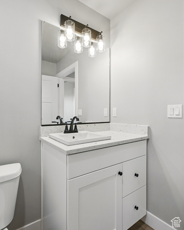 Half bath with toilet, vanity, and baseboards