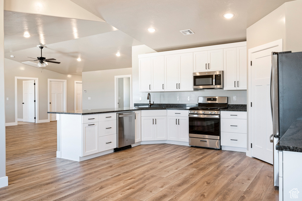 Kitchen featuring ceiling fan, vaulted ceiling, appliances with stainless steel finishes, and white cabinets