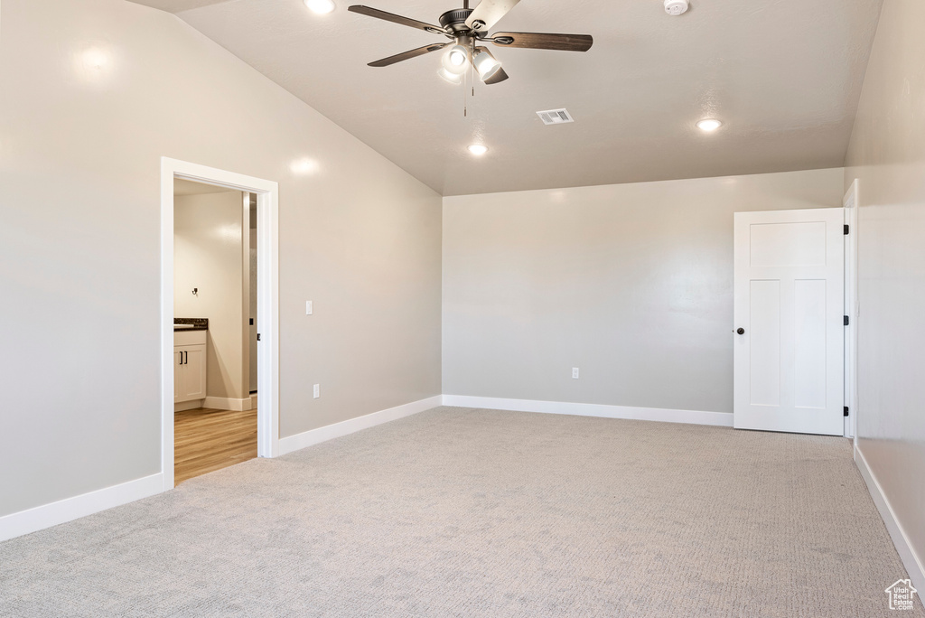 Carpeted empty room with ceiling fan and vaulted ceiling