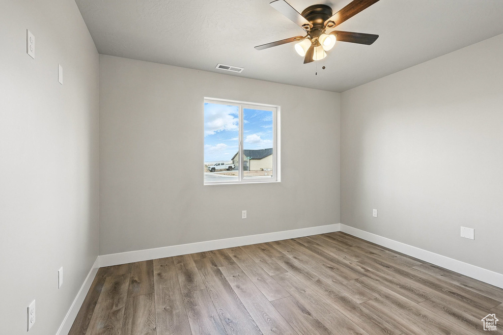 Empty room featuring visible vents, baseboards, wood finished floors, and ceiling fan