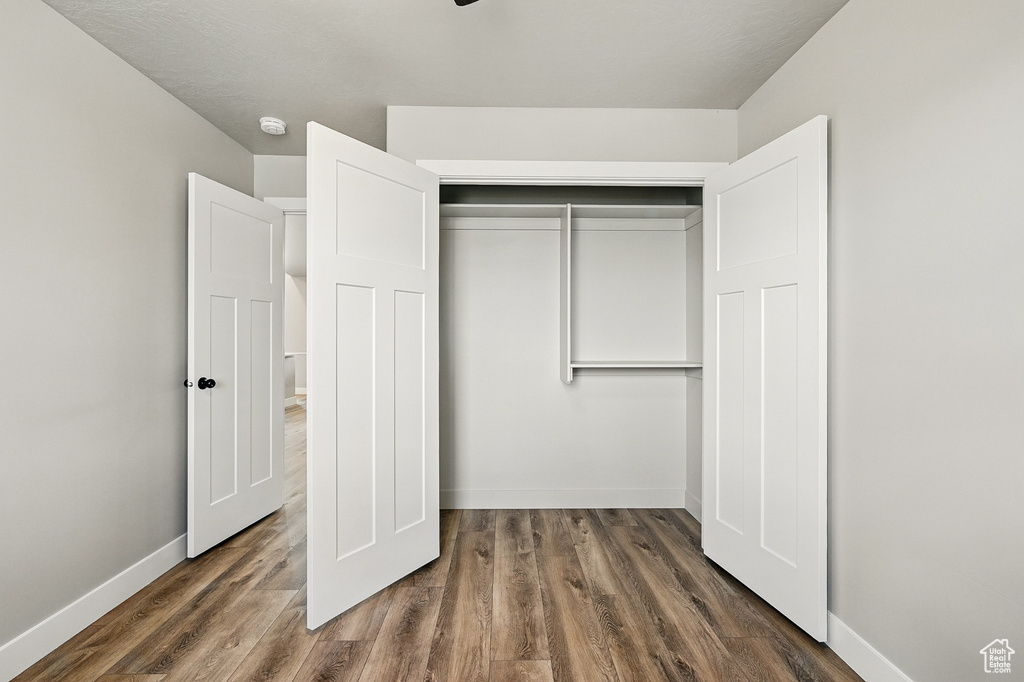 Unfurnished bedroom featuring a closet, baseboards, and wood finished floors