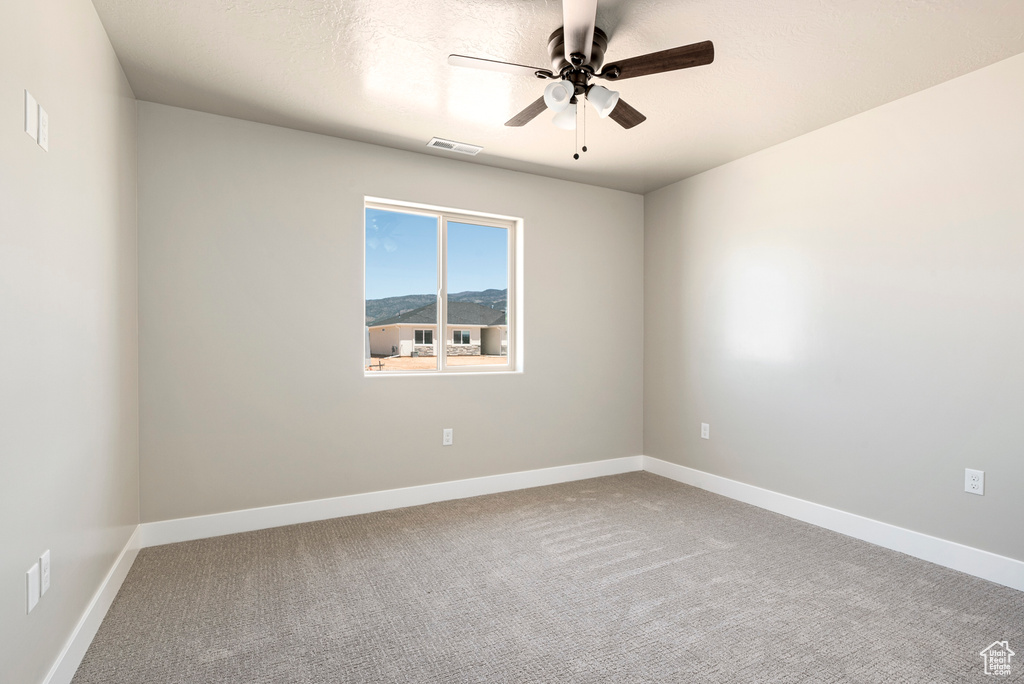 Carpeted spare room featuring ceiling fan