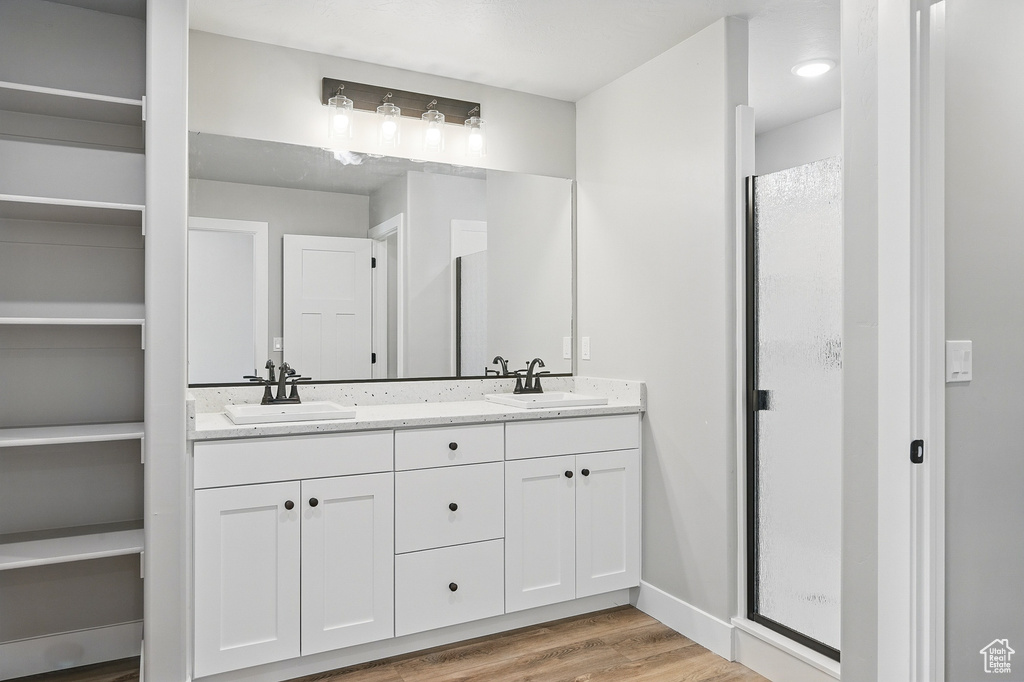 Full bath with a sink, double vanity, a stall shower, and wood finished floors