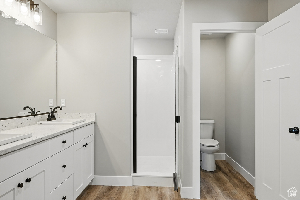 Full bath featuring baseboards, a sink, toilet, wood finished floors, and a stall shower