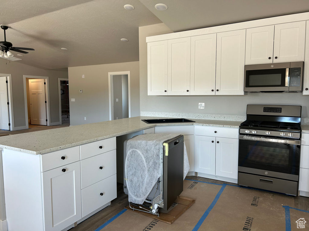 Kitchen featuring kitchen peninsula, white cabinets, appliances with stainless steel finishes, and light stone countertops