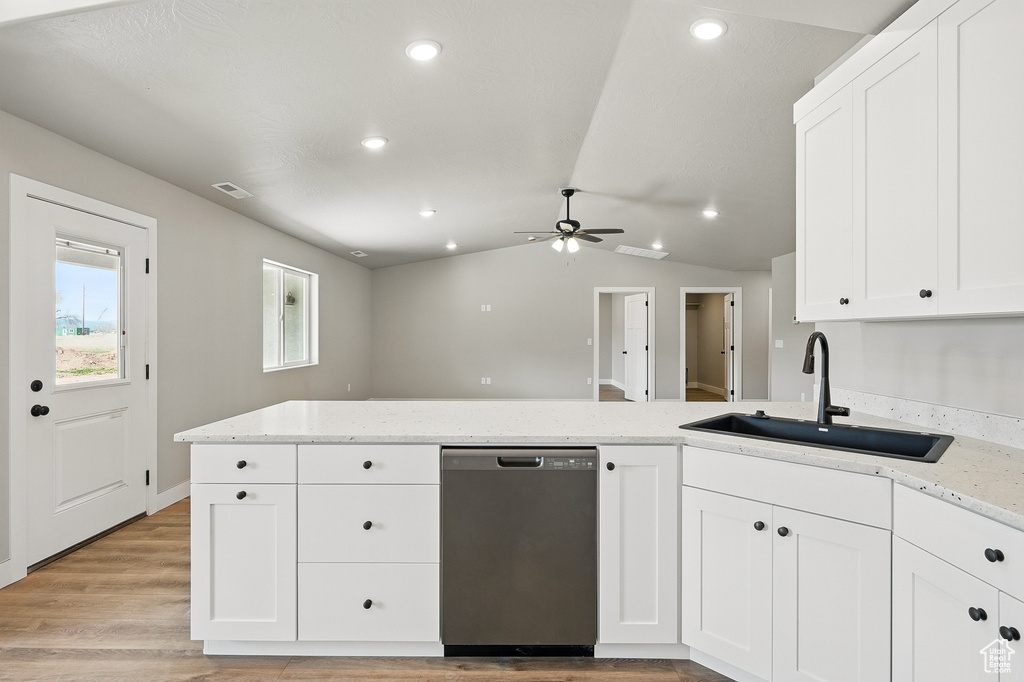 Kitchen featuring light stone counters, white cabinetry, visible vents, dishwasher, and a sink