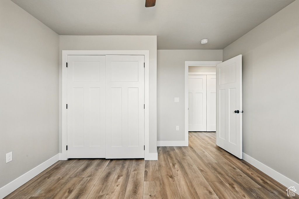 Unfurnished bedroom with a closet, baseboards, a ceiling fan, and wood finished floors