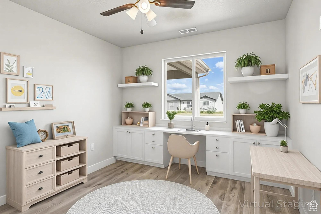 Office featuring light wood-style flooring, a ceiling fan, visible vents, built in study area, and baseboards