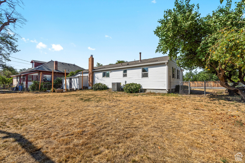 Back of property with central AC, a yard, and a shed