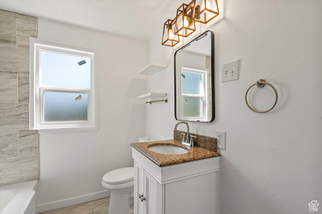 Bathroom featuring vanity, toilet, and a tub