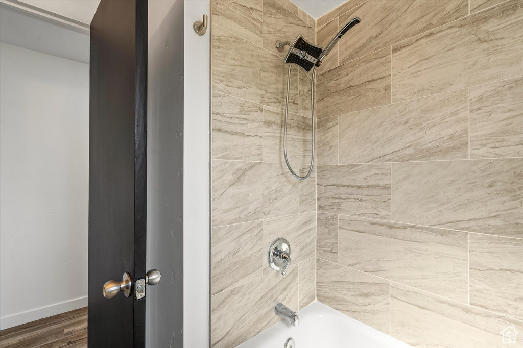 Details with tiled shower / bath and wood-type flooring