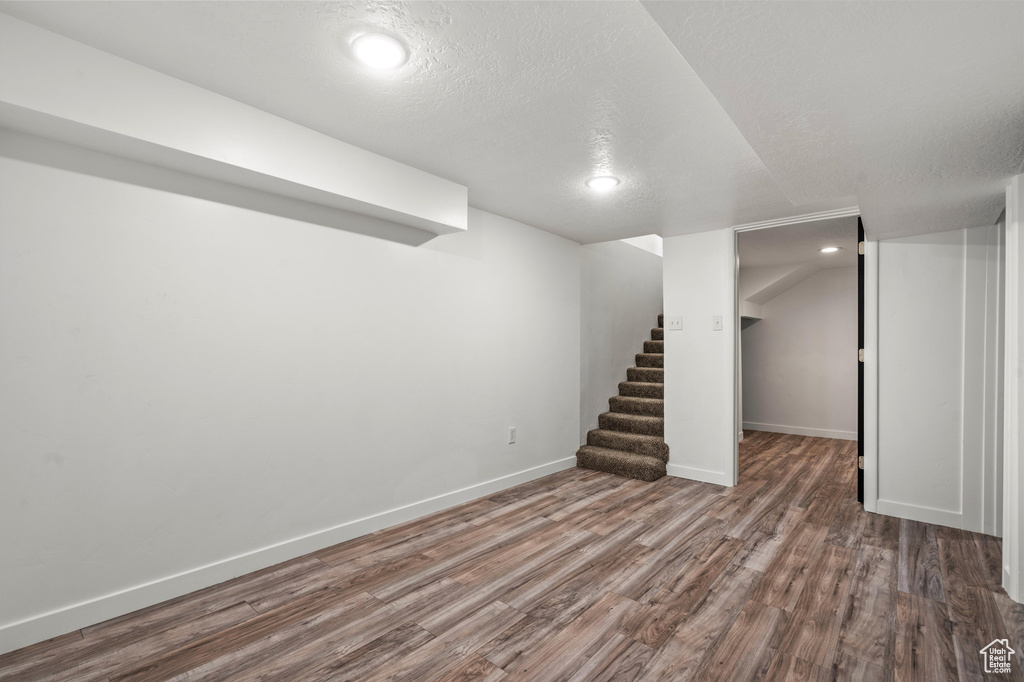 Basement featuring a textured ceiling and hardwood / wood-style flooring