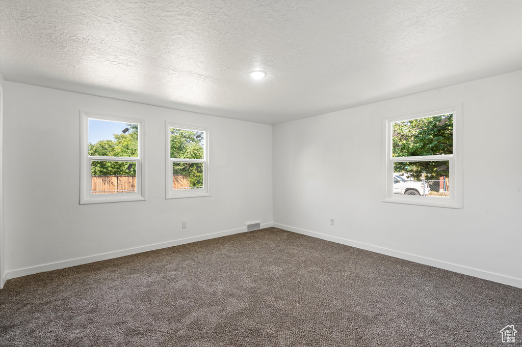 Empty room with a textured ceiling and carpet