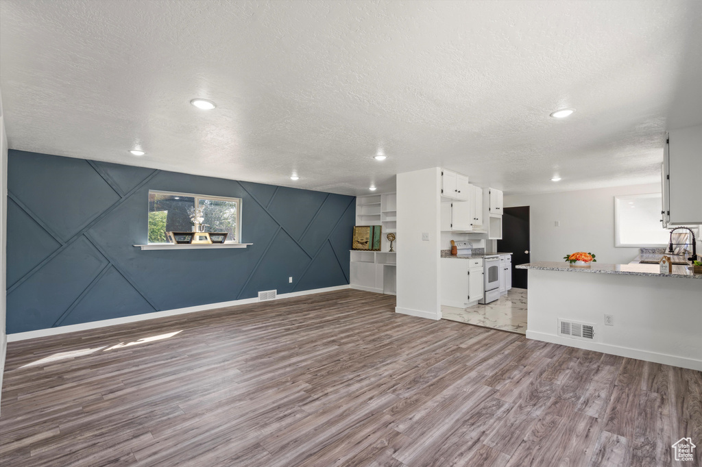 Unfurnished living room with wood-type flooring and a textured ceiling