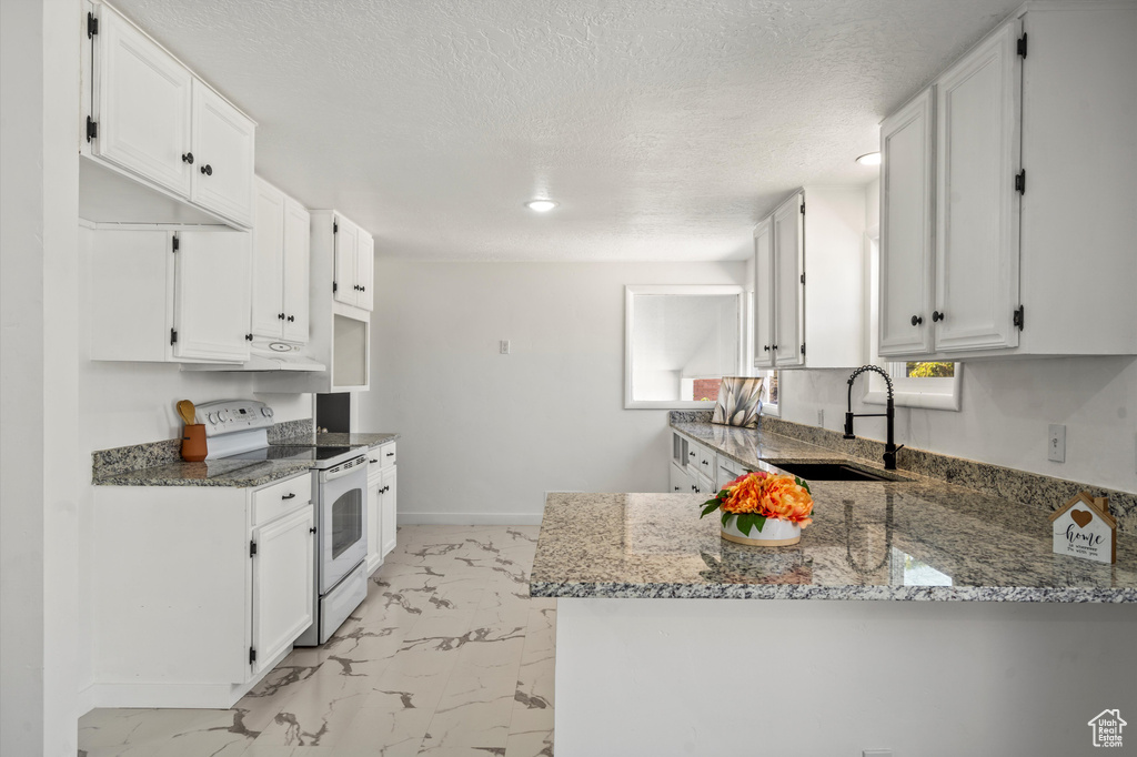 Kitchen with a textured ceiling, light stone countertops, sink, white cabinetry, and white range with electric cooktop