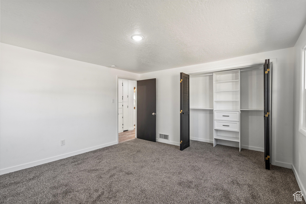 Unfurnished bedroom with a textured ceiling and carpet flooring