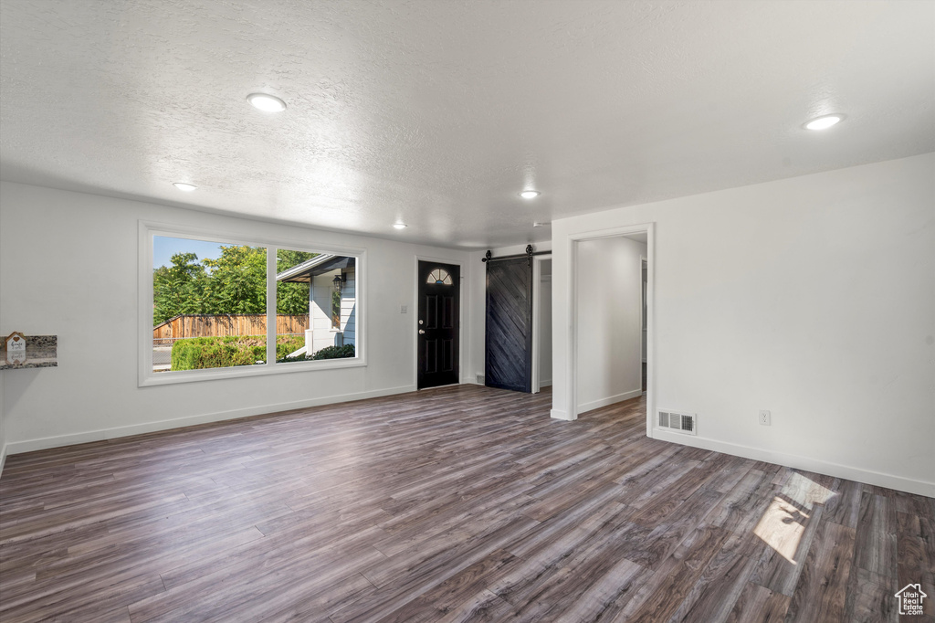 Spare room featuring a textured ceiling, a barn door, and dark hardwood / wood-style flooring