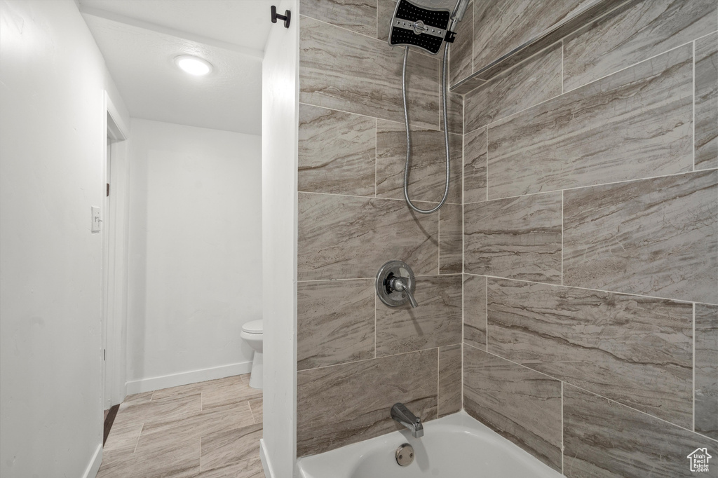 Bathroom featuring tiled shower / bath and toilet