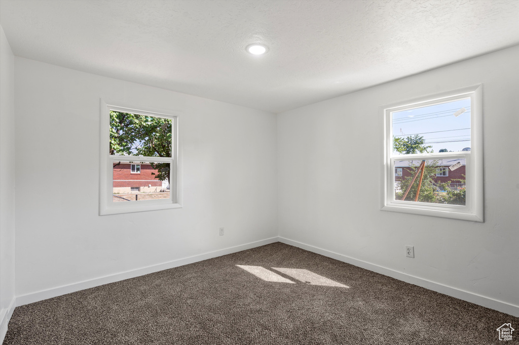 Empty room featuring a textured ceiling and carpet floors