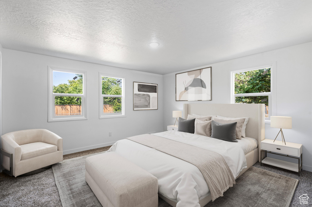 Bedroom with multiple windows, a textured ceiling, and carpet floors