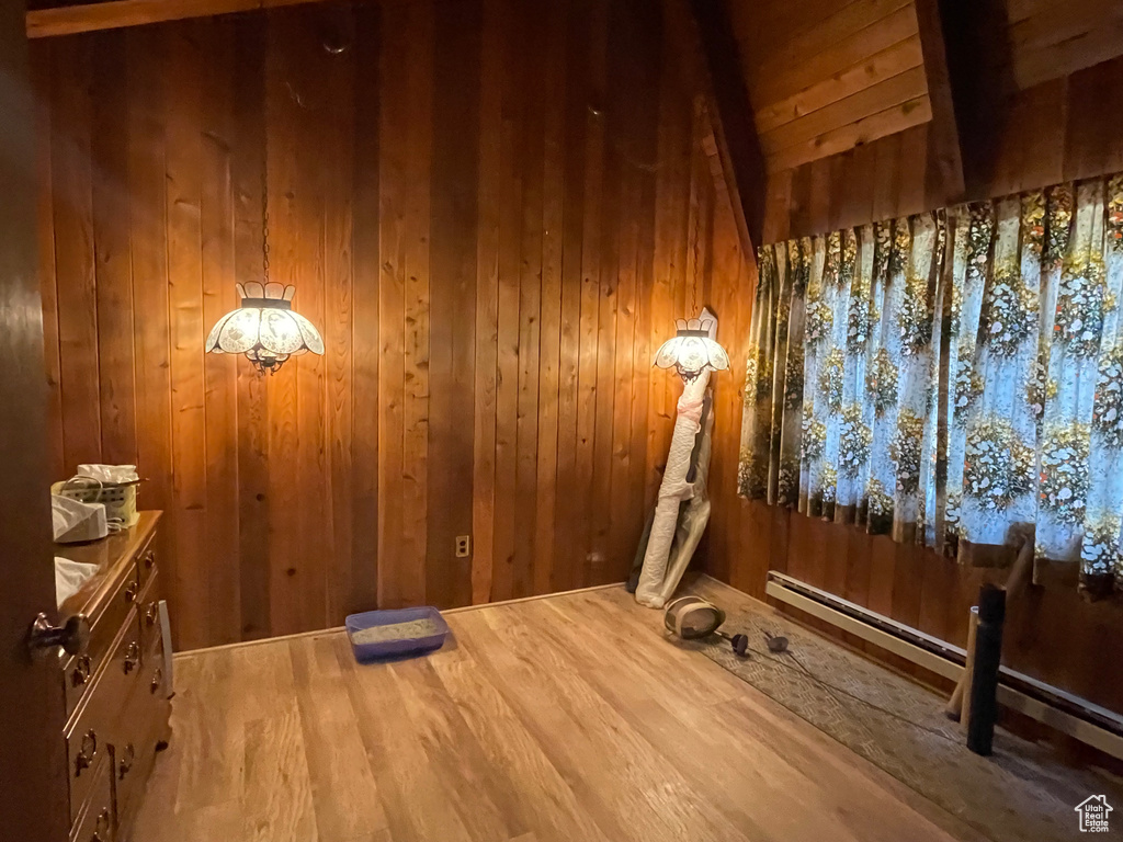 Interior space featuring lofted ceiling, wood walls, hardwood / wood-style flooring, and baseboard heating