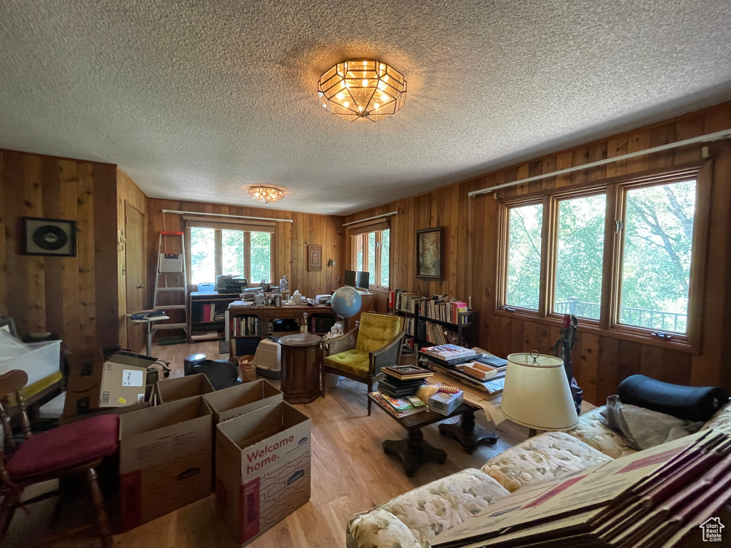 Living room featuring hardwood / wood-style flooring, wooden walls, and a textured ceiling