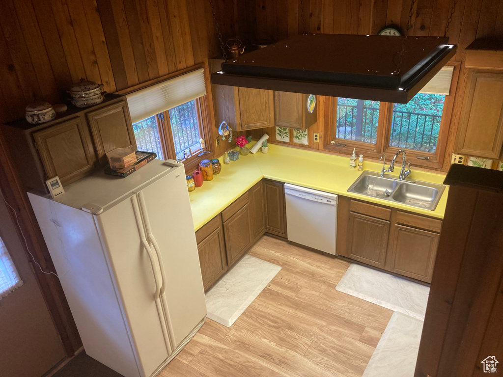 Kitchen featuring light wood-type flooring, white appliances, plenty of natural light, and wooden walls