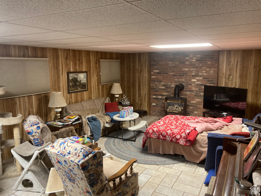 Bedroom featuring wood walls, a wood stove, and a drop ceiling