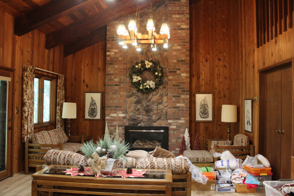 Living room featuring light hardwood / wood-style flooring, high vaulted ceiling, wooden walls, and a fireplace